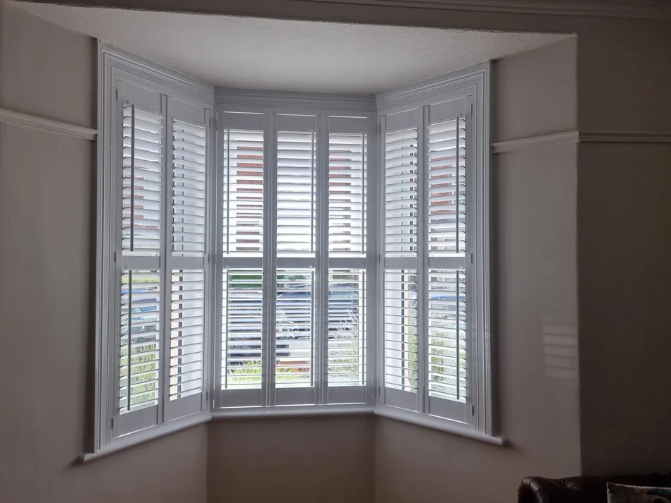 Full-height white shutters in a bay window